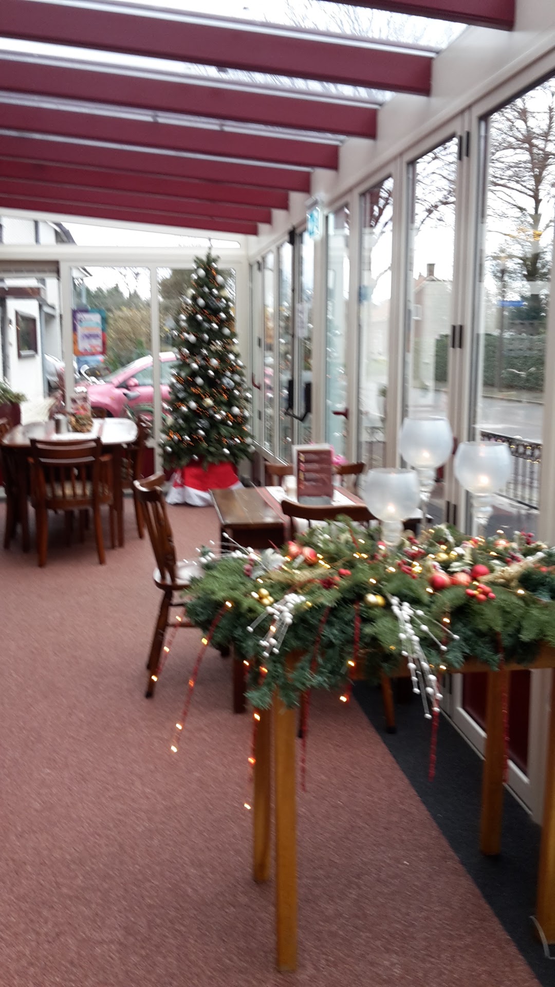 De serre in kerstsfeer, met een kerstboom en versierde tafels